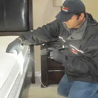 Bed bug inspection technician checking a mattress and bed frame for signs of infestation in Norfolk, VA