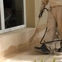 General pest control technician spraying exterior perimeter around a home in Norfolk, VA