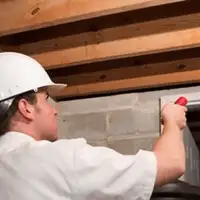Termite inspection technician checking a basement wall and framing for termite activity in Norfolk, VA