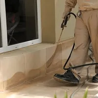 General pest control technician spraying exterior perimeter around a home in Norfolk, VA