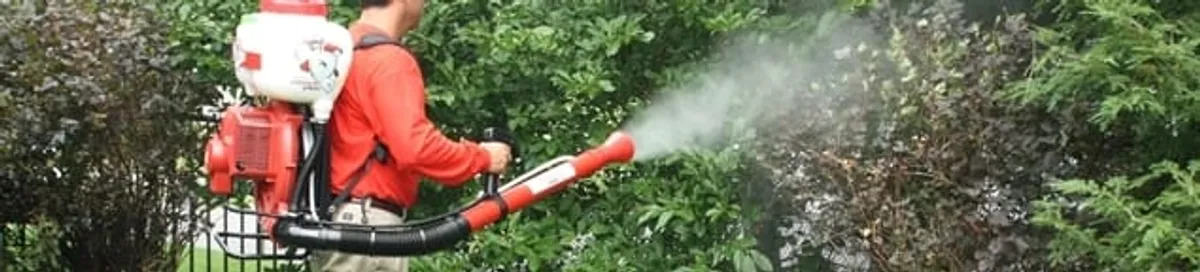 Mosquito control technician fogging shrubs and landscaping for mosquito treatment in Norfolk, VA